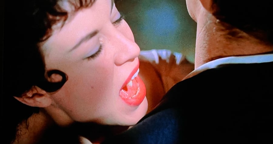 A female vampire gazes hungily at a male neck.