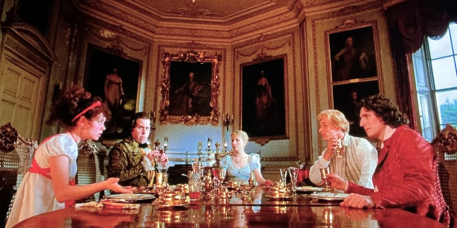 Our heroine (and anti-heroes) talk edgily around an opulent table.